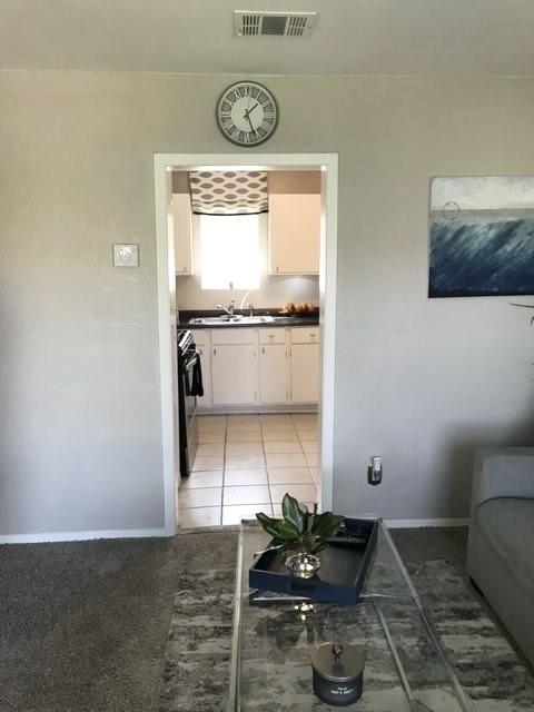 interior space with light tile patterned flooring, visible vents, and baseboards