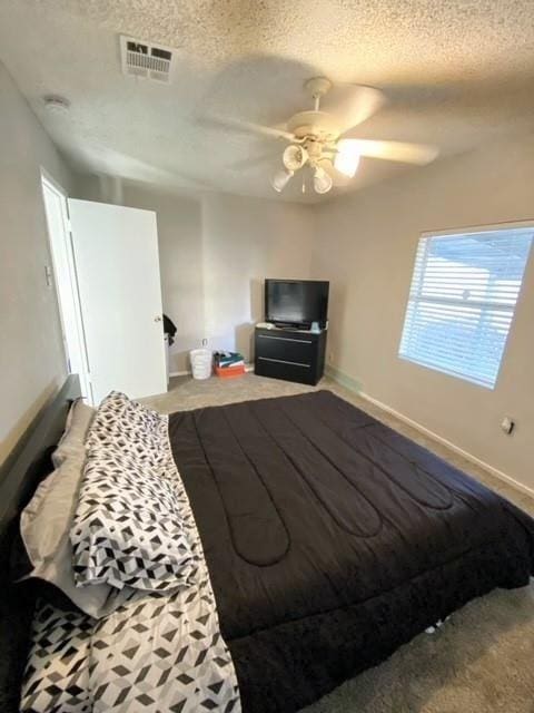 bedroom featuring visible vents, baseboards, a textured ceiling, and a ceiling fan