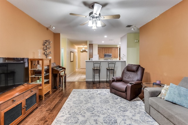 living room with dark wood finished floors, visible vents, baseboards, and ceiling fan