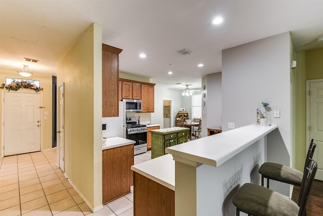 kitchen featuring a breakfast bar area, light tile patterned floors, visible vents, a peninsula, and stainless steel appliances