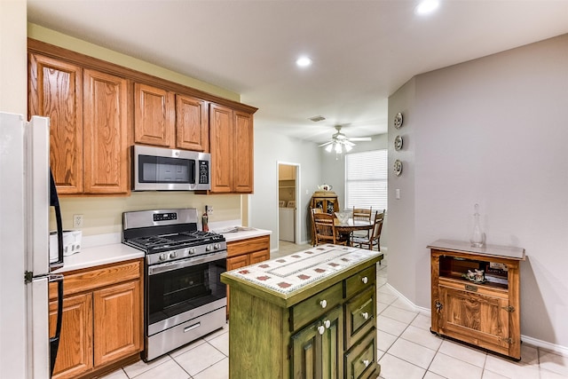 kitchen featuring light countertops, light tile patterned floors, washer / clothes dryer, and appliances with stainless steel finishes