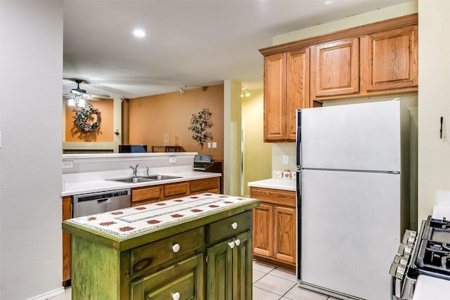 kitchen with a sink, freestanding refrigerator, gas stove, green cabinets, and dishwasher