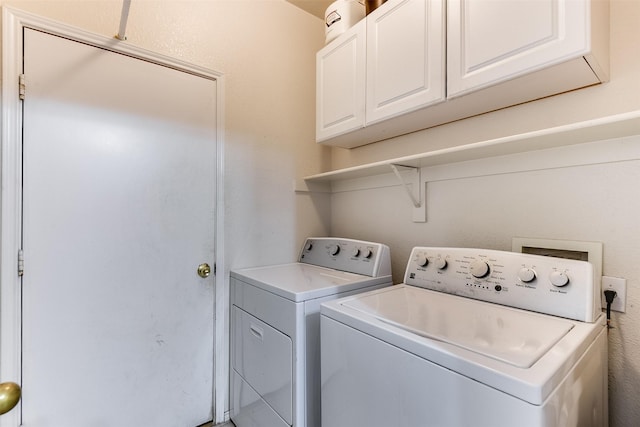 clothes washing area featuring washing machine and dryer and cabinet space