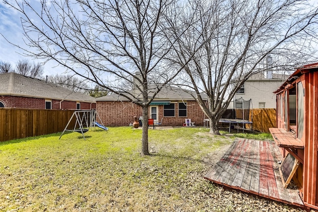 view of yard featuring a playground, a trampoline, and a fenced backyard