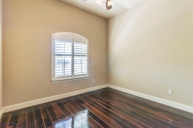 empty room with dark wood-type flooring, a ceiling fan, and baseboards