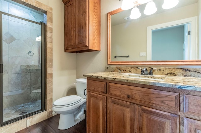 bathroom featuring vanity, a shower stall, toilet, and wood finished floors