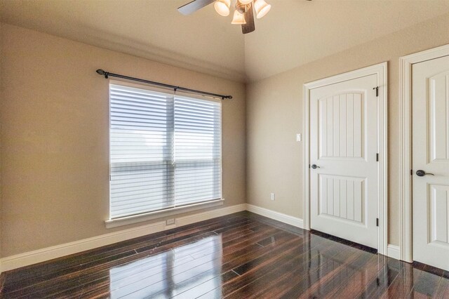 unfurnished room featuring baseboards, a ceiling fan, dark wood-style flooring, and vaulted ceiling