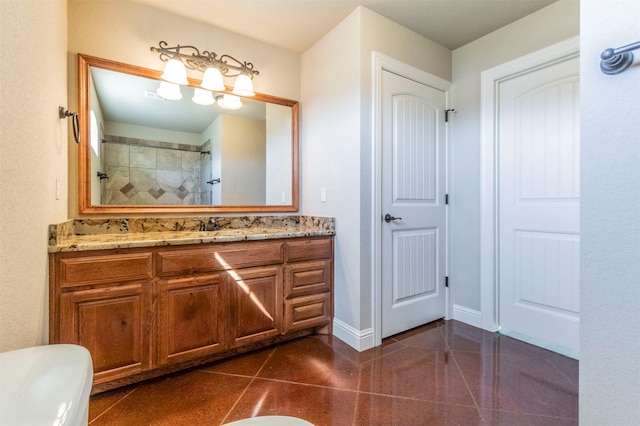 full bath featuring baseboards, vanity, and a tile shower