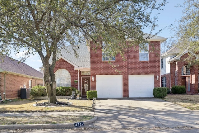 traditional home with driveway, an attached garage, a shingled roof, central air condition unit, and brick siding