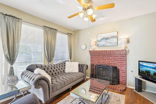 living room with a textured ceiling, wood finished floors, a fireplace, baseboards, and ceiling fan