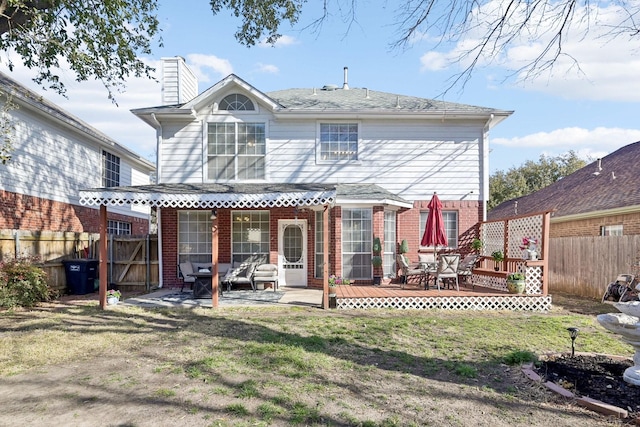 back of property with a yard, a fenced backyard, brick siding, and a chimney