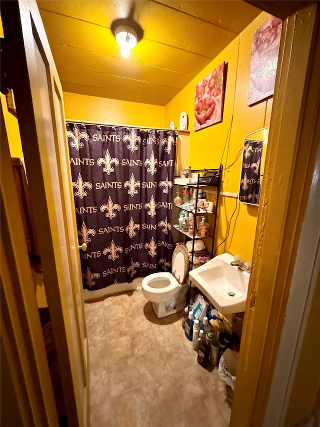 bathroom with a sink, curtained shower, and toilet