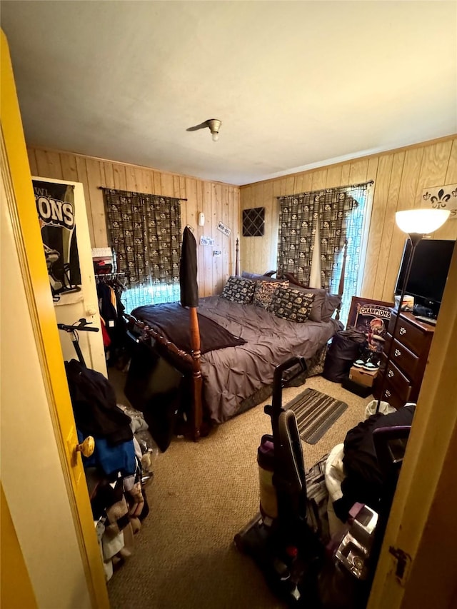 carpeted bedroom featuring wood walls