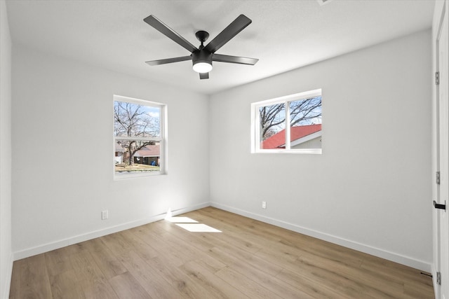 empty room featuring light wood-style flooring, a ceiling fan, and baseboards