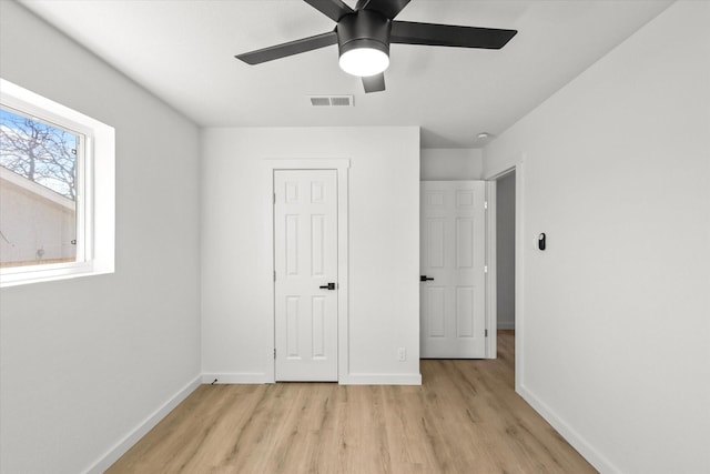 unfurnished bedroom featuring a ceiling fan, light wood-style flooring, baseboards, and visible vents