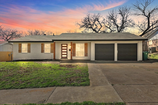 mid-century inspired home featuring driveway, cooling unit, a front yard, a garage, and brick siding