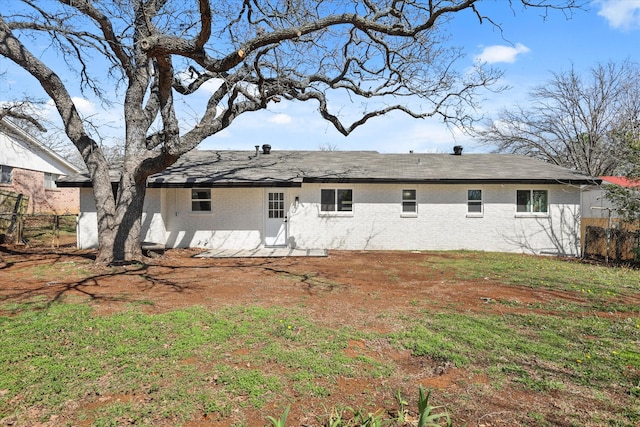 back of property with brick siding, a yard, and fence