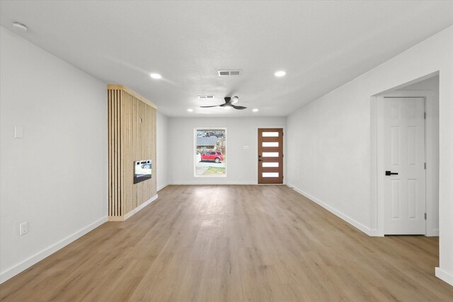 unfurnished living room with light wood finished floors, visible vents, baseboards, ceiling fan, and a sink