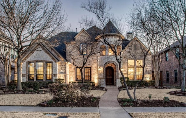 french country style house with brick siding and stone siding