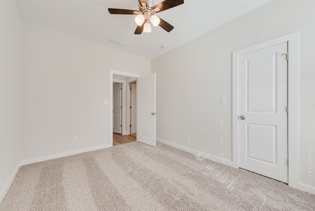 unfurnished bedroom with a ceiling fan, visible vents, light colored carpet, and baseboards