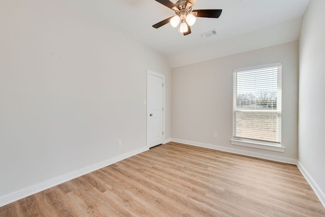 empty room with a ceiling fan, visible vents, baseboards, light wood finished floors, and lofted ceiling