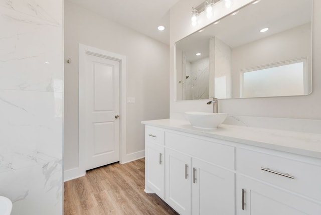 full bathroom featuring recessed lighting, a marble finish shower, wood finished floors, and vanity