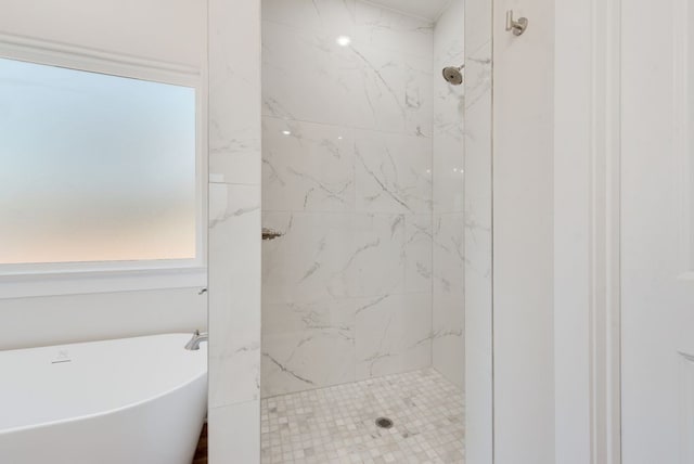 full bath featuring a marble finish shower and a freestanding tub