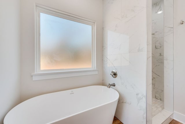 bathroom with a marble finish shower and a freestanding tub