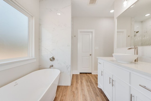 bathroom with visible vents, wood finished floors, a freestanding bath, walk in shower, and vanity