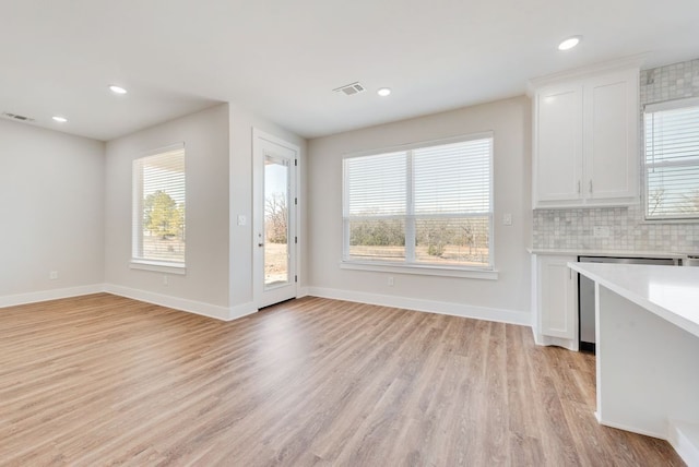 unfurnished dining area with visible vents, plenty of natural light, light wood-style flooring, and baseboards