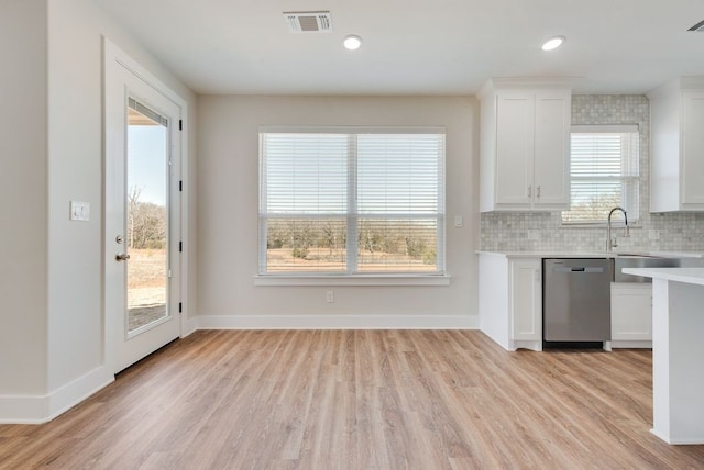 kitchen featuring visible vents, light countertops, white cabinets, dishwasher, and backsplash