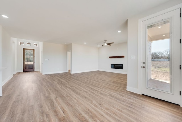 unfurnished living room with light wood finished floors, baseboards, ceiling fan, recessed lighting, and a glass covered fireplace