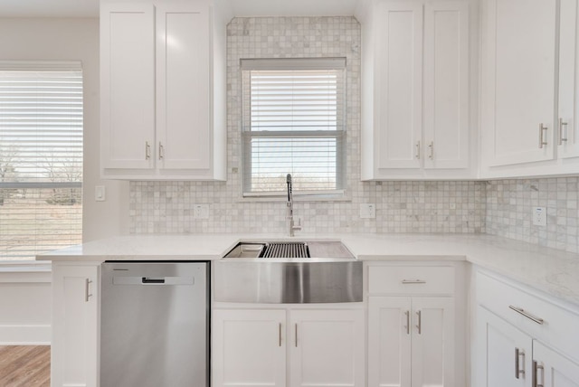 kitchen featuring backsplash, dishwasher, light countertops, white cabinetry, and a sink