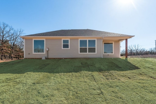 rear view of property featuring a yard and roof with shingles