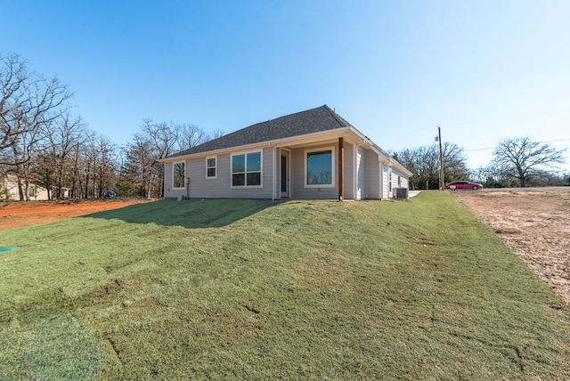 rear view of property featuring a yard and cooling unit