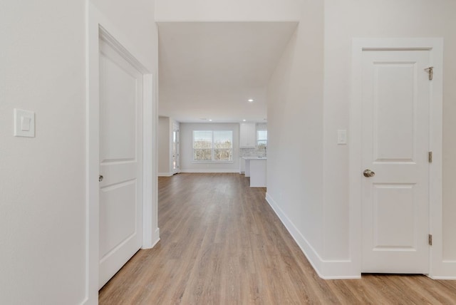 corridor with recessed lighting, baseboards, and light wood finished floors