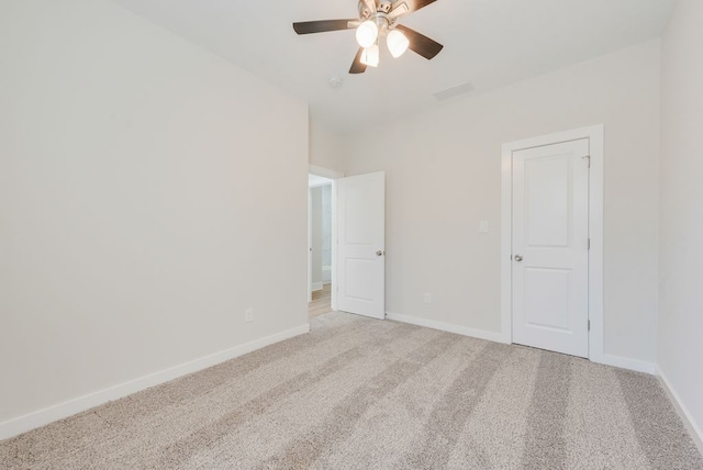 empty room with light carpet, visible vents, a ceiling fan, and baseboards