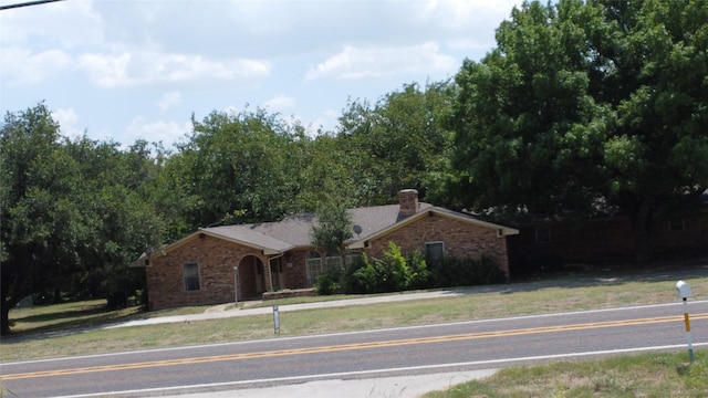 single story home featuring brick siding and a chimney