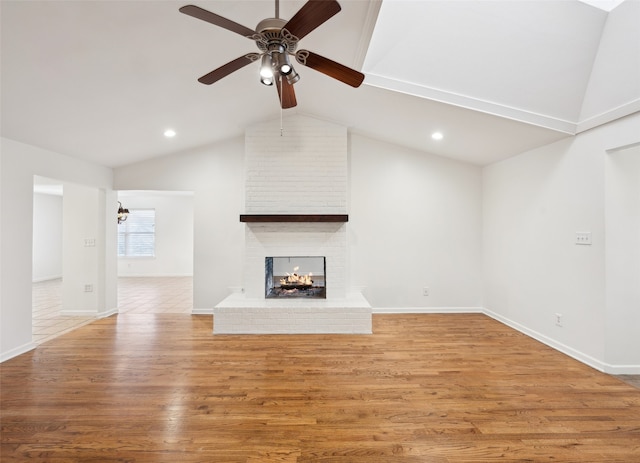 unfurnished living room with baseboards, lofted ceiling, light wood-style flooring, and a fireplace