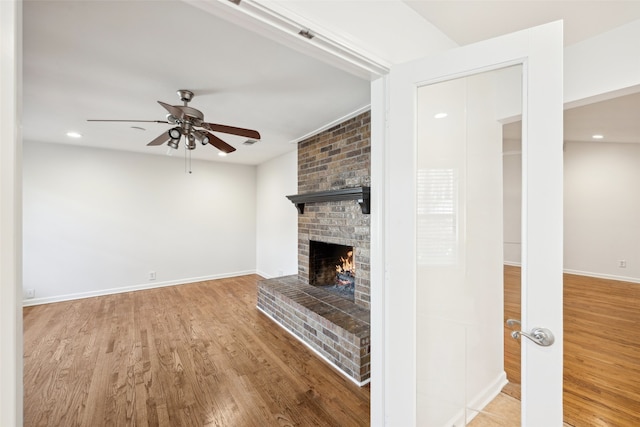 unfurnished living room with baseboards, recessed lighting, a fireplace, wood finished floors, and a ceiling fan