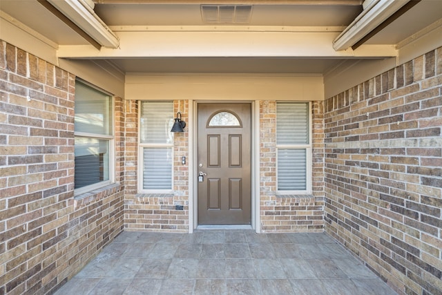 doorway to property with brick siding and visible vents