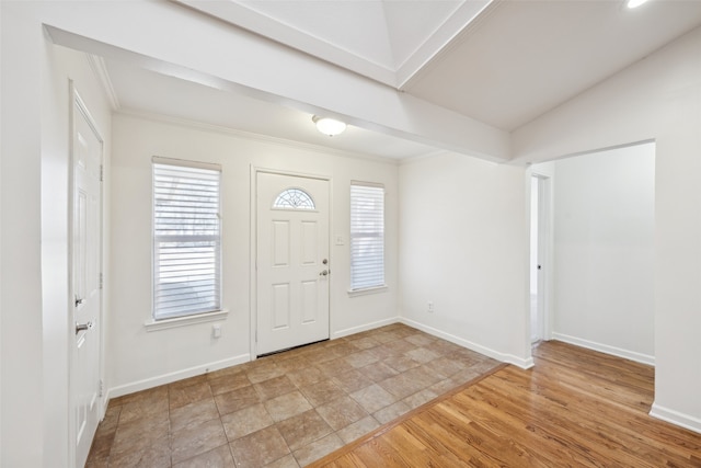 foyer featuring crown molding, wood finished floors, baseboards, and lofted ceiling