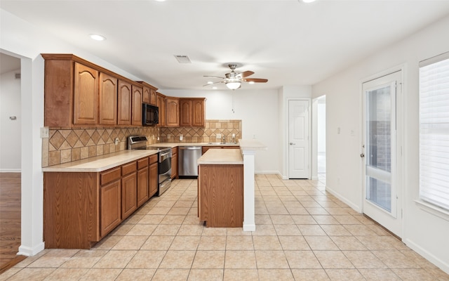 kitchen with tasteful backsplash, light countertops, light tile patterned floors, brown cabinetry, and stainless steel appliances