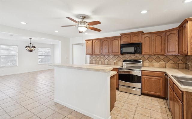 kitchen featuring light tile patterned flooring, stainless steel electric range, light countertops, black microwave, and ceiling fan with notable chandelier