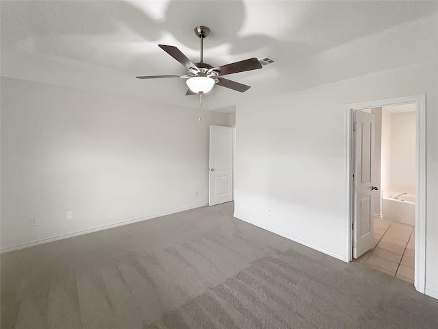 spare room with carpet flooring, visible vents, a ceiling fan, and baseboards