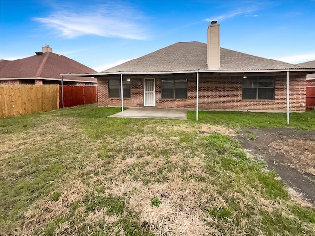 back of house with a patio area, a lawn, brick siding, and fence