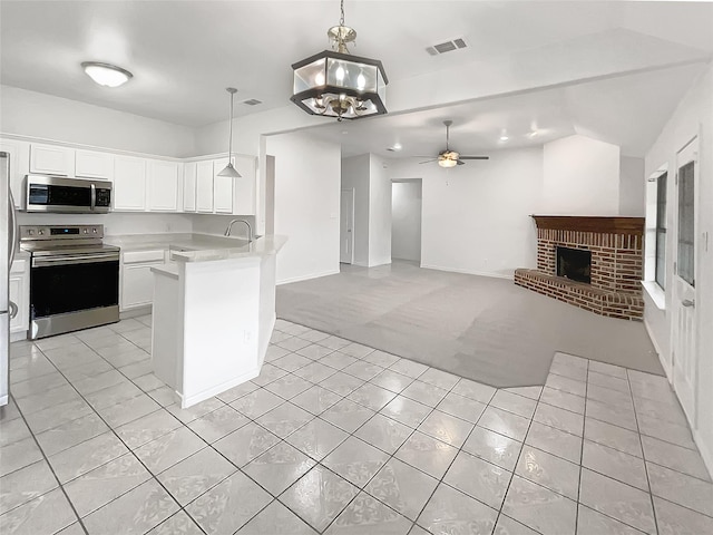 kitchen featuring visible vents, a peninsula, a fireplace, appliances with stainless steel finishes, and open floor plan