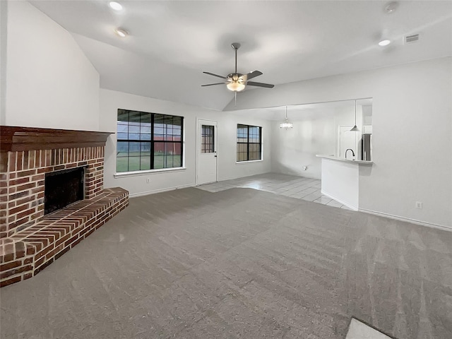 unfurnished living room featuring visible vents, carpet floors, a fireplace, and ceiling fan with notable chandelier