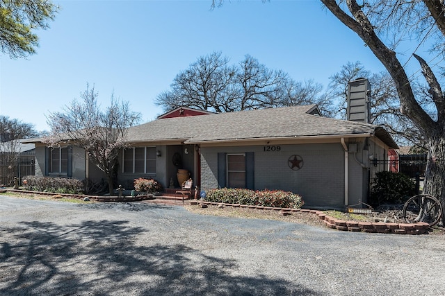 single story home with brick siding, a chimney, and a shingled roof