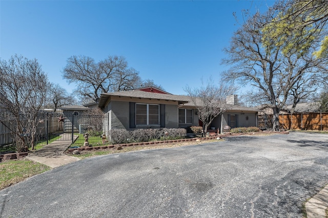 single story home with a gate, fence, and a chimney